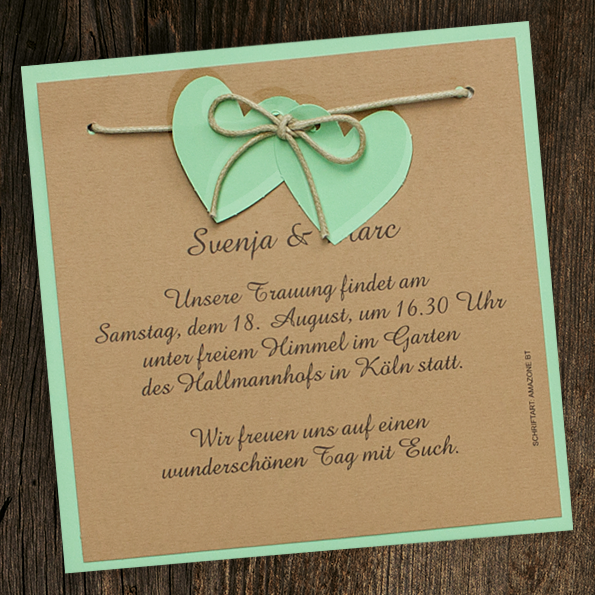 Hochzeitseinladungen aus grünem Naturkarton und braunem Jraftkarton mit zwei an eine Kordel geknüpften Herzen Hochzeitseinladungen im Country-Style. Grüner Naturkarton kombiniert mit braunem Kraftkarton.